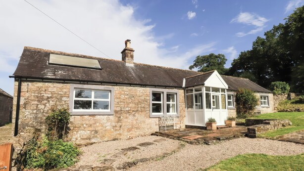 A stone house with a gabled roof, a conservatory, and a gravel driveway. - Allergarth Barn (Carlisle)