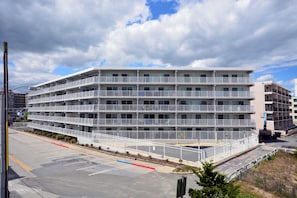 A multi-story hotel with balconies, a parking lot, and a clear sky.