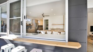 A modern kitchen with a dining area visible through a sliding glass door. - Ginger's - Pet Friendly - 4 Min Walk to Beach (Callala Beach)