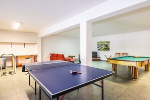 Une pièce équipée d’une table de ping-pong, d’un billard et d’un tapis de course.