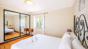Une chambre à coucher avec un grand lit, un miroir, une fenêtre et une table de chevet.