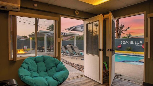 Quarto com vista para uma piscina, uma cadeira verde e uma porta que dá para o exterior.