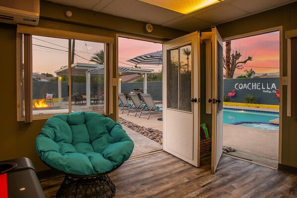 A room with a view of a pool, a chair, and a door leading outside.