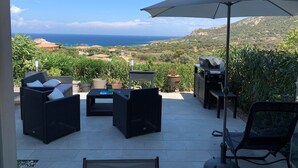 An outdoor patio with wicker furniture, a grill, and a view of the ocean. - Apartment T2 Sea View, Air-conditioned, 4 People swimming pool in the residence  (Lumio)