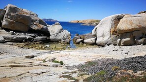 Un paysage côtier rocheux, avec de gros blocs de pierre et une eau d’un bleu limpide.