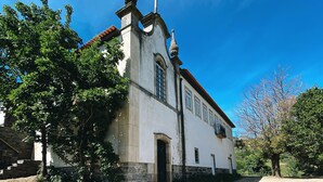 Un edificio blanco con techo de tejas, base de piedra y un pequeño porche.