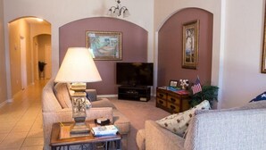 A living room with a sofa, a coffee table, a TV, and a lamp. - IPG Florida Vacation Homes Bella Piazza Resort (Clermont)