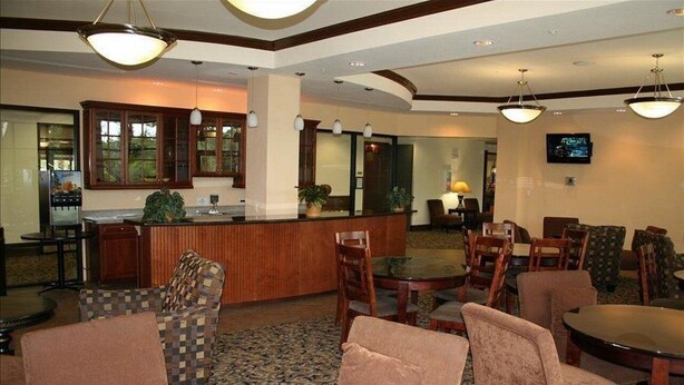 A hotel lobby with a reception desk, seating area, and a television screen. - IPG Florida Vacation Homes Bella Piazza Resort (Clermont)