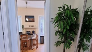 Un passadís amb una zona de menjador al fons, una planta en test i un gran mirall.
