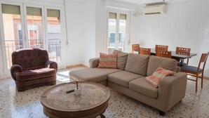A living room with a sofa, armchair, coffee table, and a dining area with chairs and a table.