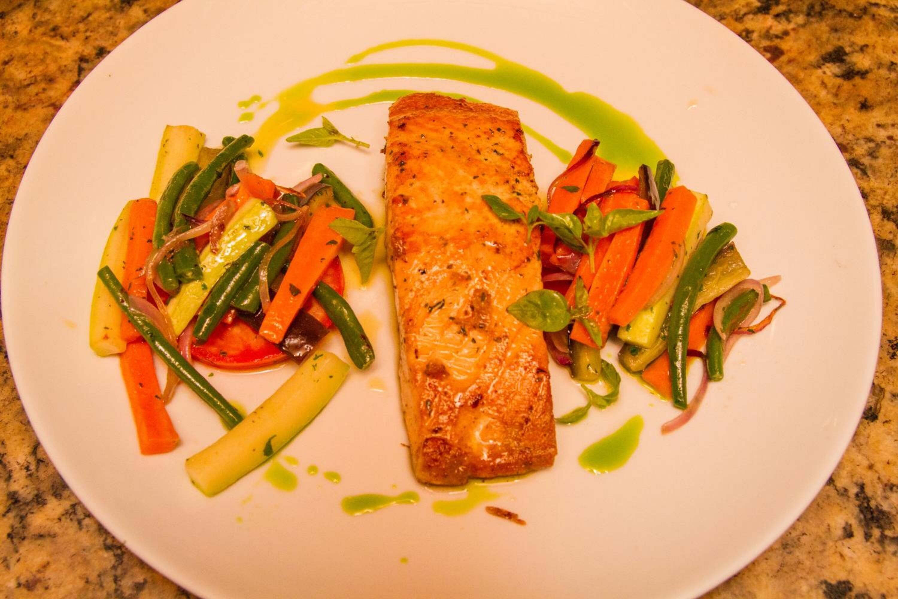 Un plato con un trozo de salmón, zanahorias y judías verdes.