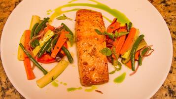 Un plato con un trozo de salmón, zanahorias y judías verdes.
