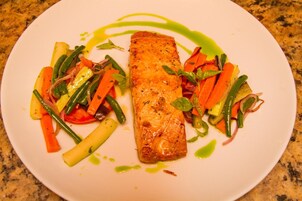 Un plato con un trozo de salmón, zanahorias y judías verdes.