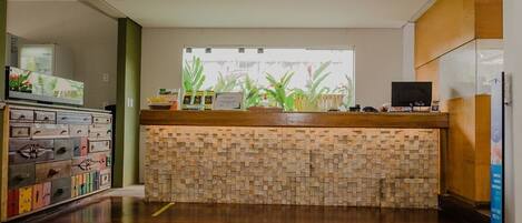 A modern kitchen with a wooden countertop, a stone backsplash, and a window with plants.