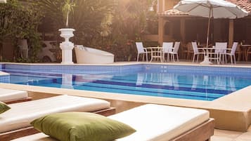 Una piscina al aire libre, sillones reclinables de piscina