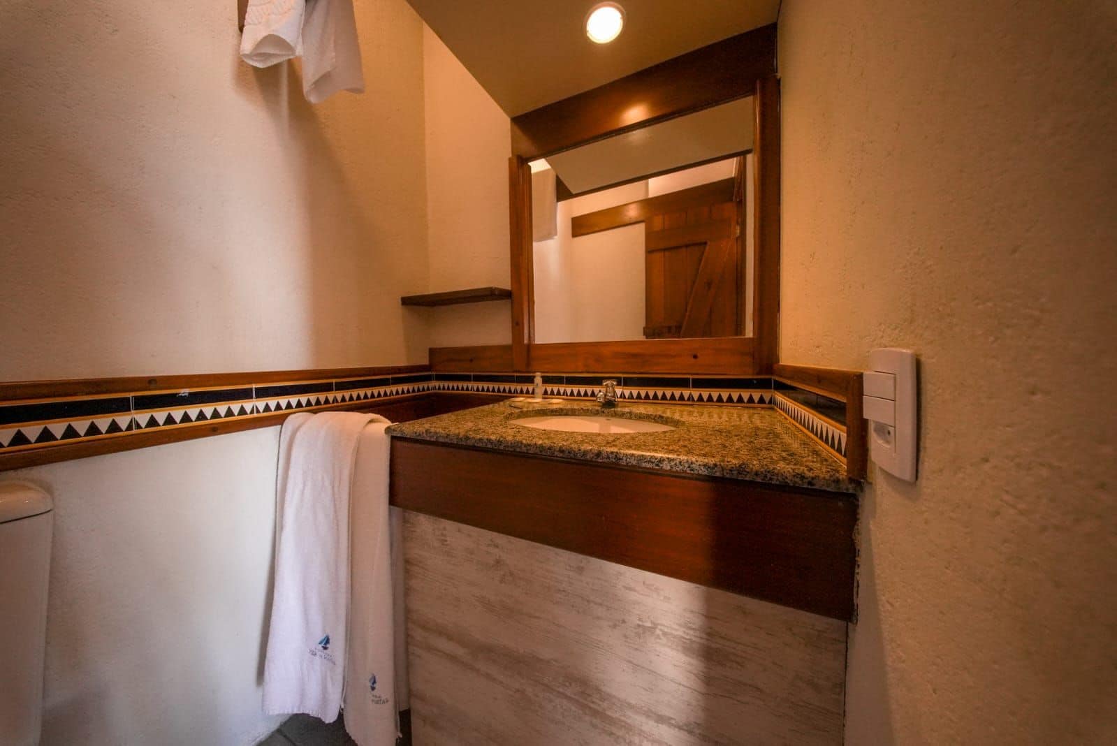 A bathroom with a granite countertop sink, a towel hanging on the wall, and a wooden door in the background.