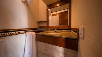 Un baño con lavamanos de encimera de granito, una toalla colgada en la pared y una puerta de madera al fondo.