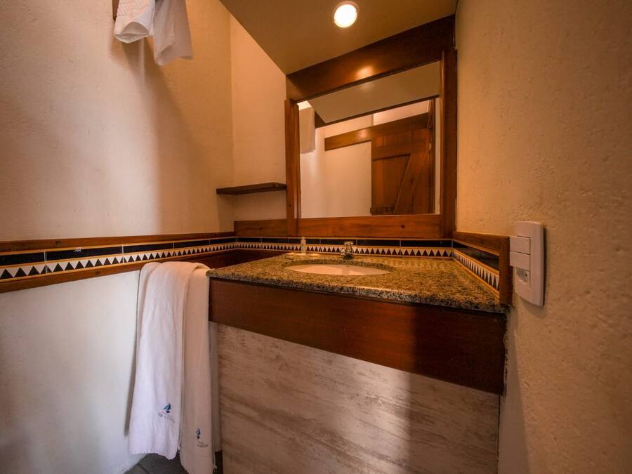 A bathroom with a granite countertop sink, a towel hanging on the wall, and a wooden door in the background.