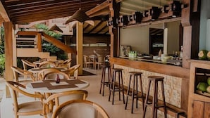 A restaurant with wooden furniture, a bar area, and a view of the outdoor garden. - Pousada Pier do Pontal (Ilhéus)
