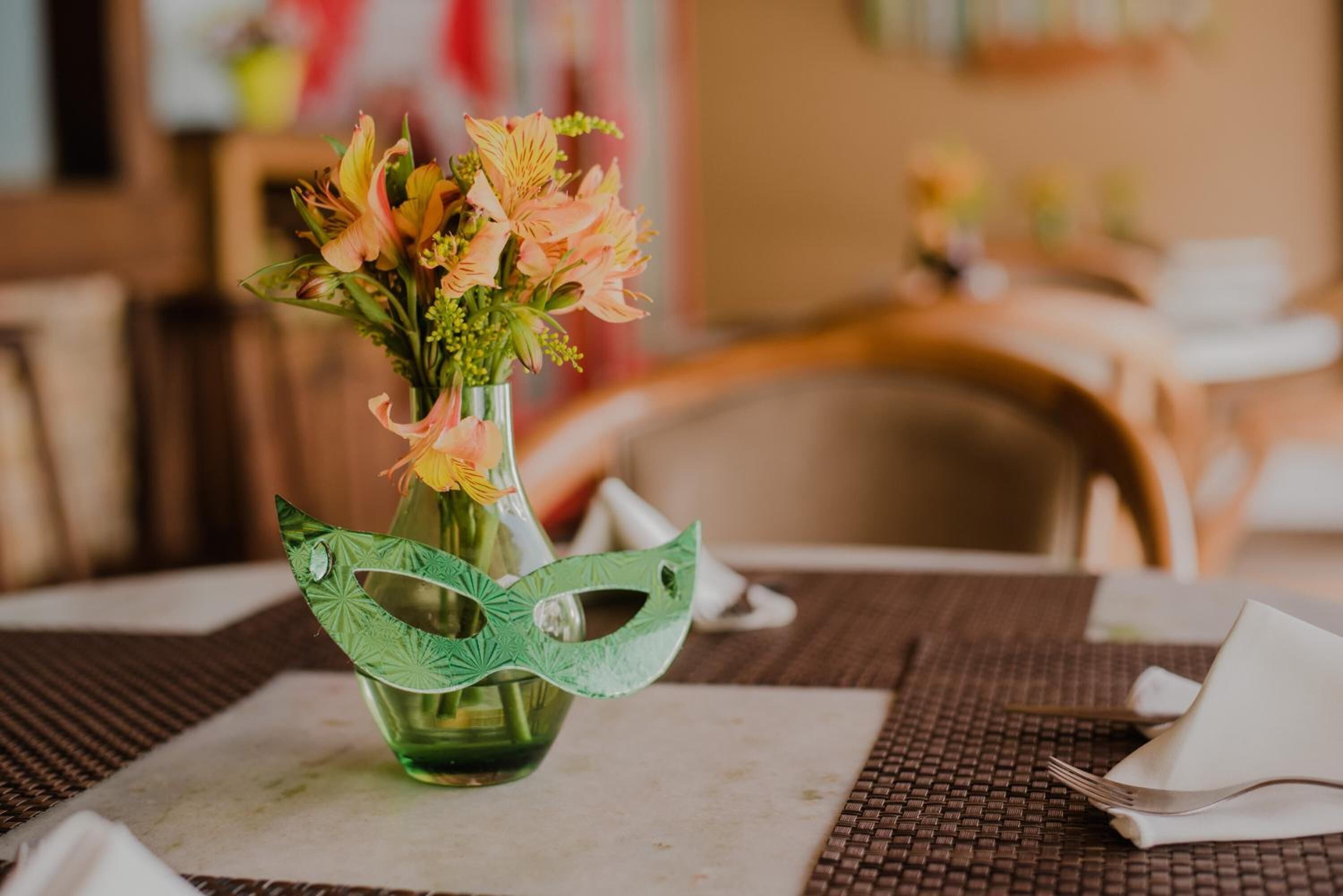 A table with a vase of flowers and a decorative mask.