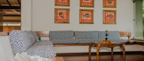 A living room with a patterned sofa, a wooden coffee table, and framed artwork on the wall.