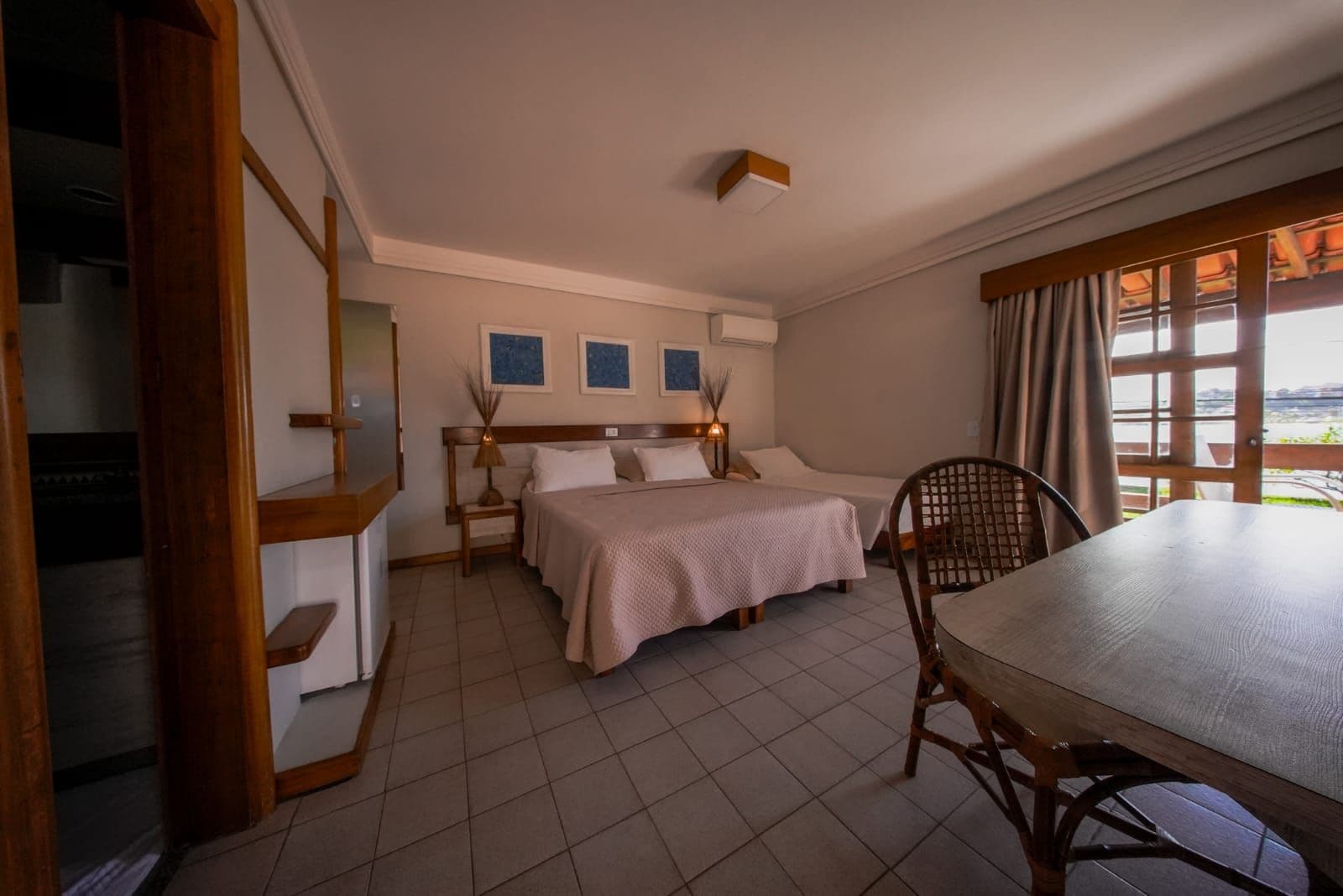 A hotel room with a bed, a desk, and a view of the outside.