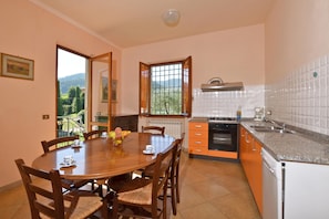 Enjoy meals at the round dining table surrounded by comfortable chairs in this well-equipped kitchen.