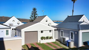 Una hilera de casas modernas de un piso, con garaje, antena parabólica y vista despejada al mar.