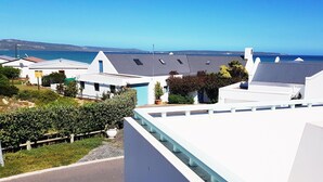 A coastal residential area with modern white houses, a clear blue sky, and a view of the sea. - 99 Steps, Langebaan 8-sleeper (Langebaan)