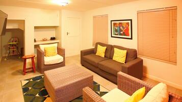 A living room with a brown sofa, two armchairs, a small table, and a colorful rug.