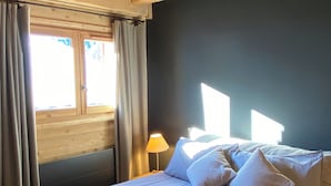 Une pièce avec un lit, une fenêtre avec des rideaux, une lampe et un plafond en bois.