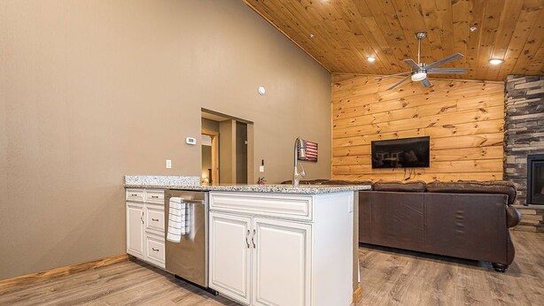 A kitchen with white cabinets, a granite countertop, and a wooden ceiling.