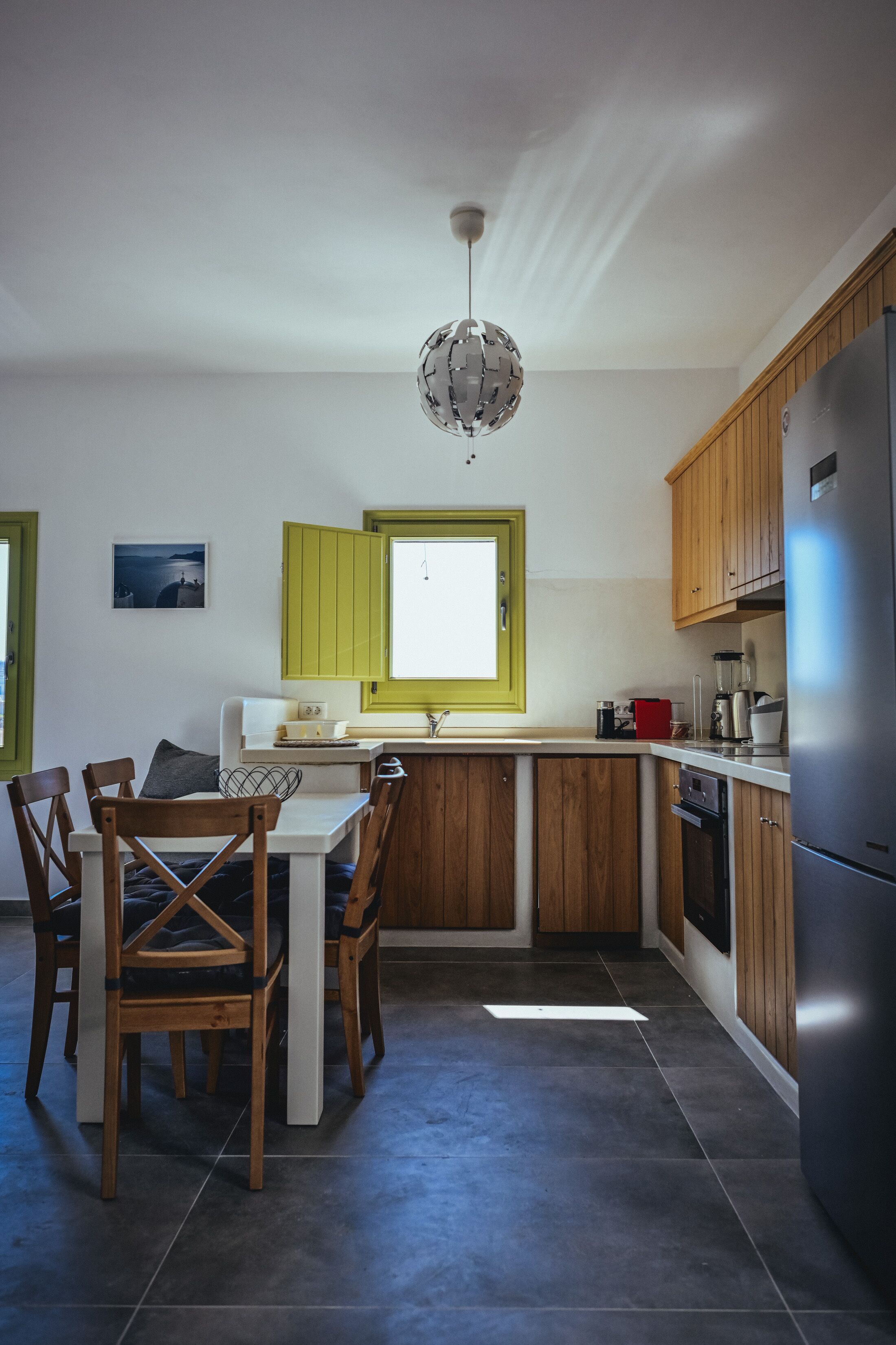 Une cuisine compacte avec des meubles en bois, un îlot central et un réfrigérateur en acier inoxydable.