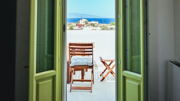 Quarto com uma grande porta de vidro que dá para uma área de estar externa com vista para o mar.