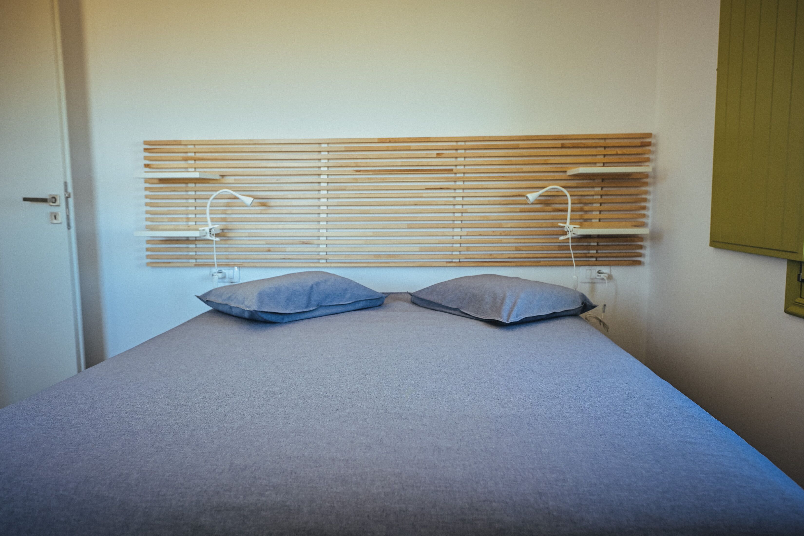 A bed with a wooden headboard, two pillows, and bedside lamps.