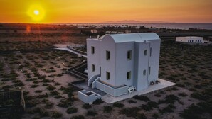 Um edifício moderno com telhado plano, várias janelas e um pequeno pátio com área para sentar ao ar livre.