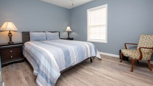 A bedroom with a bed, two bedside tables with lamps, a chair, and a window. - Seneca Spirit: Gorgeous Views of Seneca Lake! (Geneva)