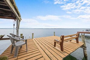 A wooden deck with a table and chairs, overlooking a calm body of water. - Seneca Spirit: Gorgeous Views of Seneca Lake! (Geneva)