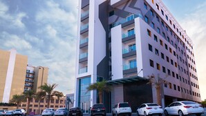 A modern hotel with a unique architectural design, featuring multiple balconies and a glass facade. - Resivation Hotel (Dubai)