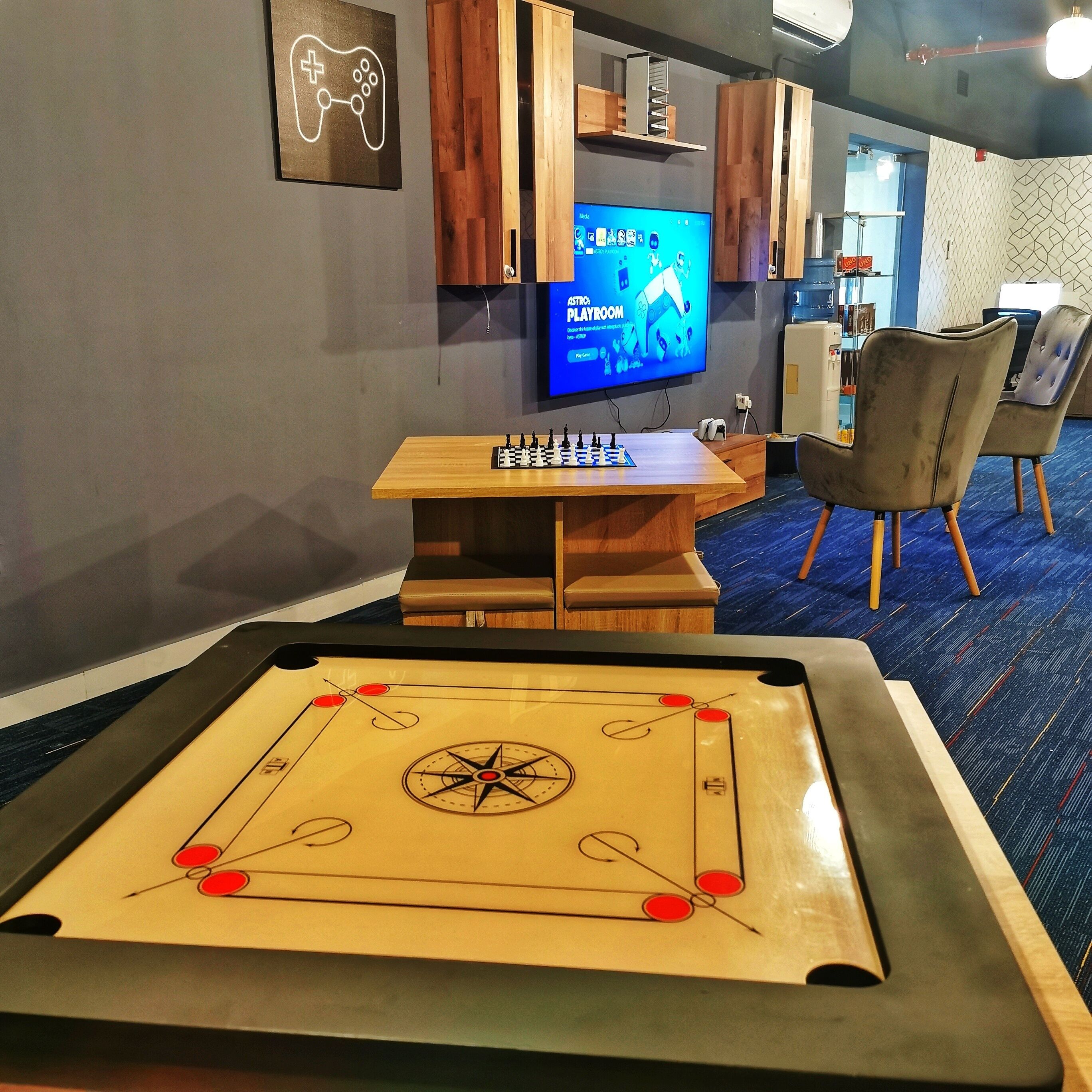 Ett rum med ett träbord, en tv som visar spelet ”ASTROS PLAYROOM” och ett bordfotbollsspel.