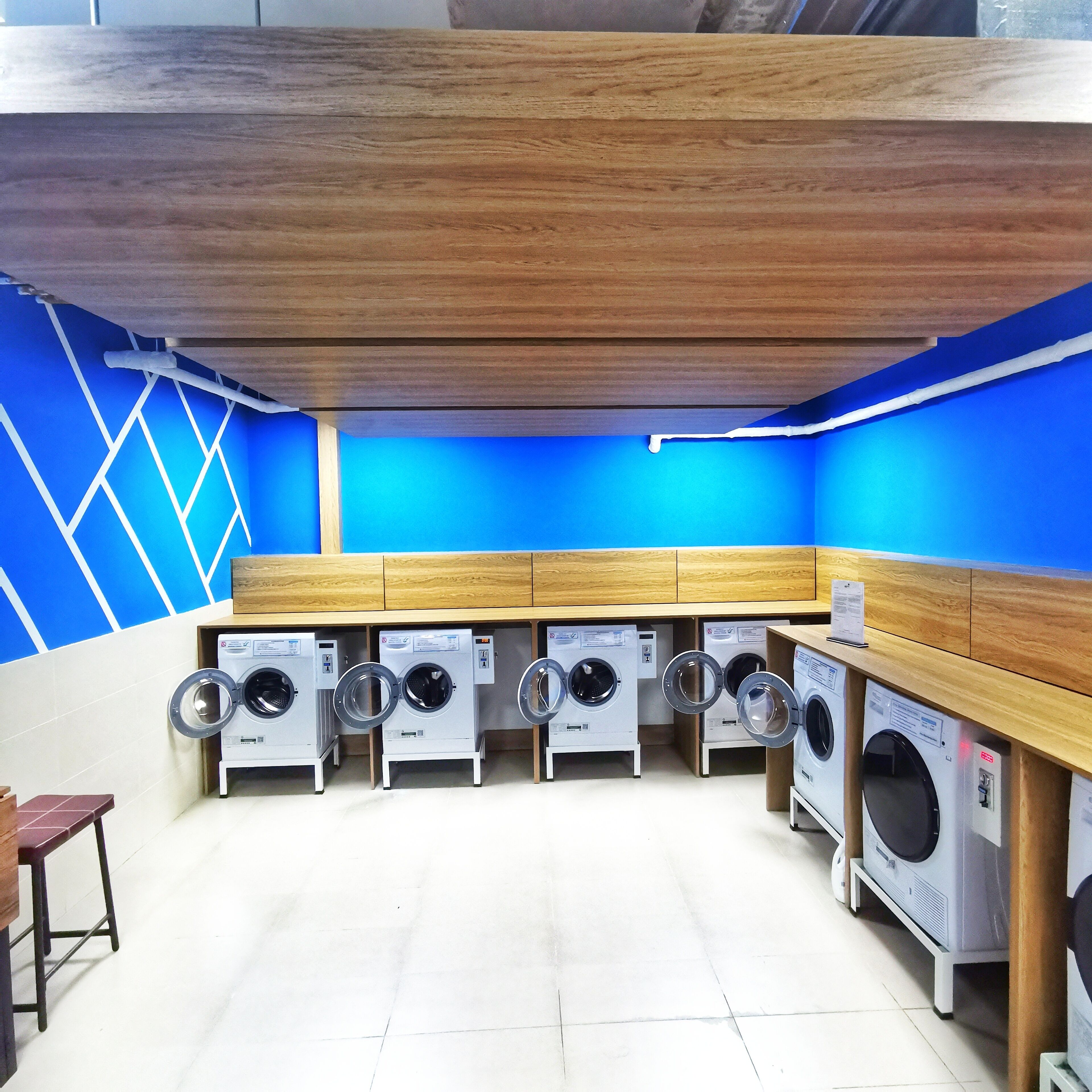 A laundry facility with multiple washing machines and wooden cabinets.