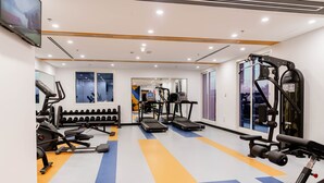 A gym with treadmills, weight machines, and dumbbells. - Resivation Hotel (Dubai)