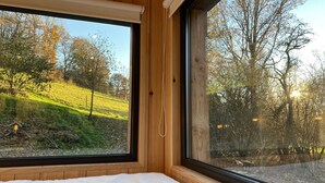 Une chambre avec une grande fenêtre, des murs en bois et un lit.