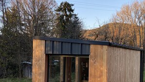 Une petite cabane en bois avec une fenêtre en verre et un matelas à l’intérieur.