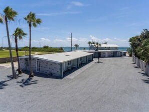 A beachfront motel with a covered parking area, palm trees, and a view of the ocean. - Flip Flops and Bikini Tops #1 - Direct River Access (Cocoa Beach)