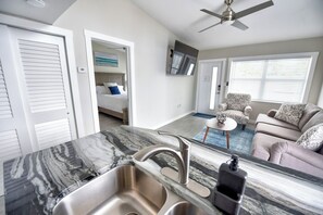 A modern kitchen with a marble countertop, stainless steel sink, and a ceiling fan. - Flip Flops and Bikini Tops #1 - Direct River Access (Cocoa Beach)