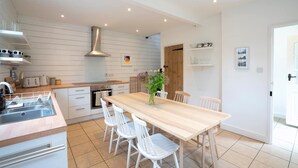 Une cuisine moderne avec des meubles blancs, une table à manger en bois et des chaises blanches.