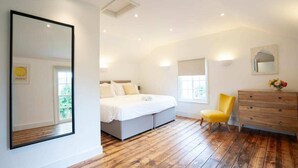 Une chambre à coucher avec un lit, une chaise, une commode et un grand miroir.