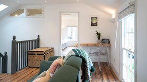 Un salon chaleureux avec un canapé vert, une commode en bois et un bureau avec une chaise.