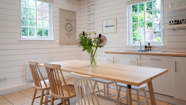 Une cuisine moderne avec des meubles en bois, un îlot central et de grandes fenêtres.
